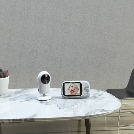 3.2 inch baby monitor on a marble table next to a plant and chair, showcasing wireless 2-way communication.